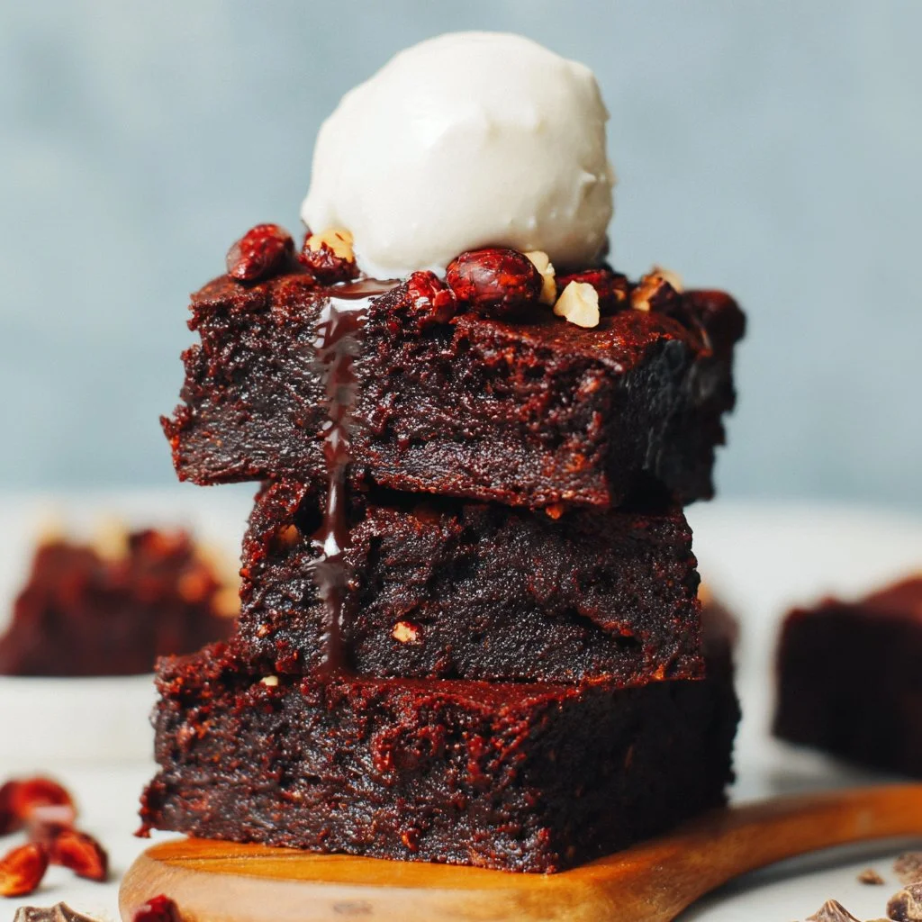 Fudgy sweet potato brownies on a white plate with a chocolate drizzle.