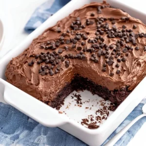 Slice of easy chocolate poke cake topped with chocolate frosting and sprinkles