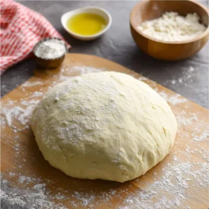 A homemade pizza dough ball on a wooden countertop, ready to be shaped.
