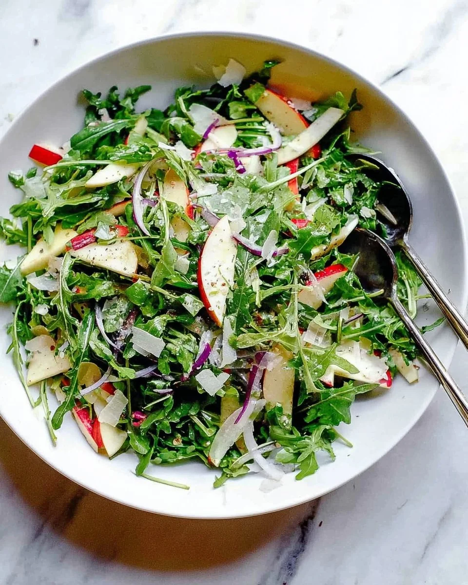 Arugula salad topped with sliced apples and parmesan cheese