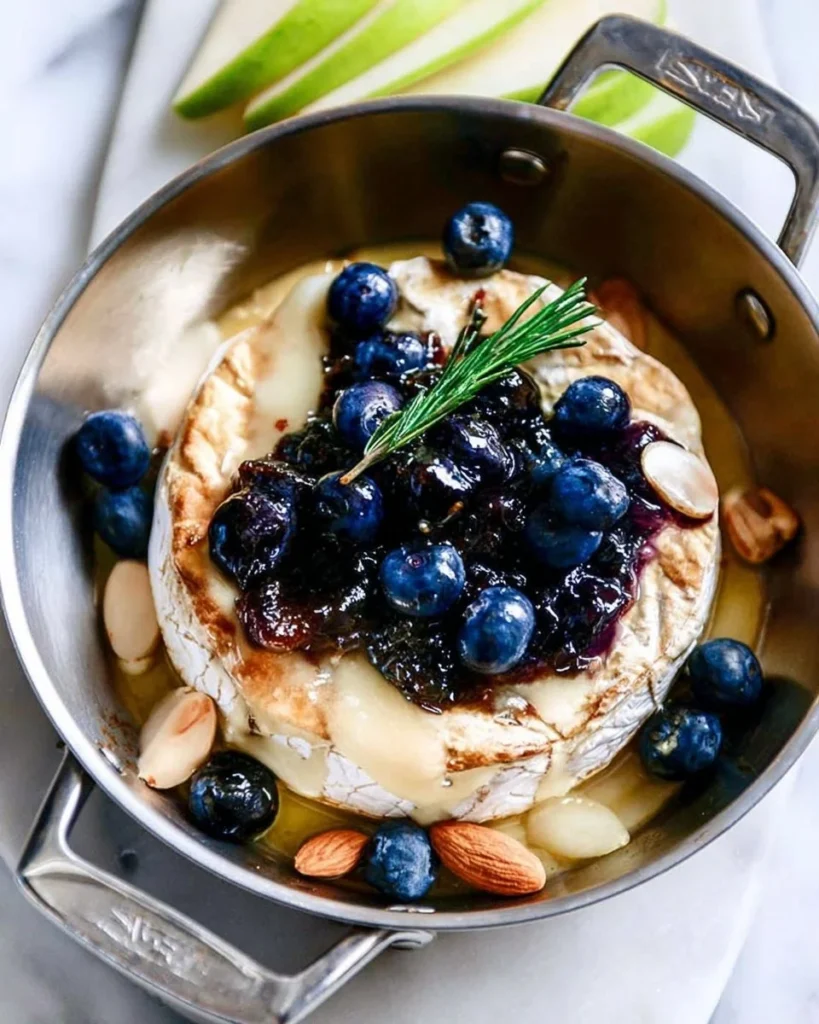 Delicious baked brie topped with blueberries and lemon marmalade served on a platter.