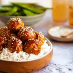Baked teriyaki chicken meatballs on a plate with sauce and vegetables