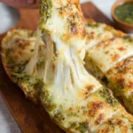 Cheesy pesto garlic bread with melted cheese and fresh herbs.