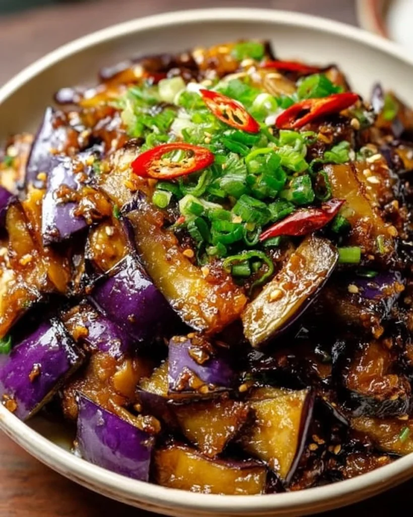 Chinese eggplant in garlic sauce served in a bowl, showcasing vibrant colors and textures.