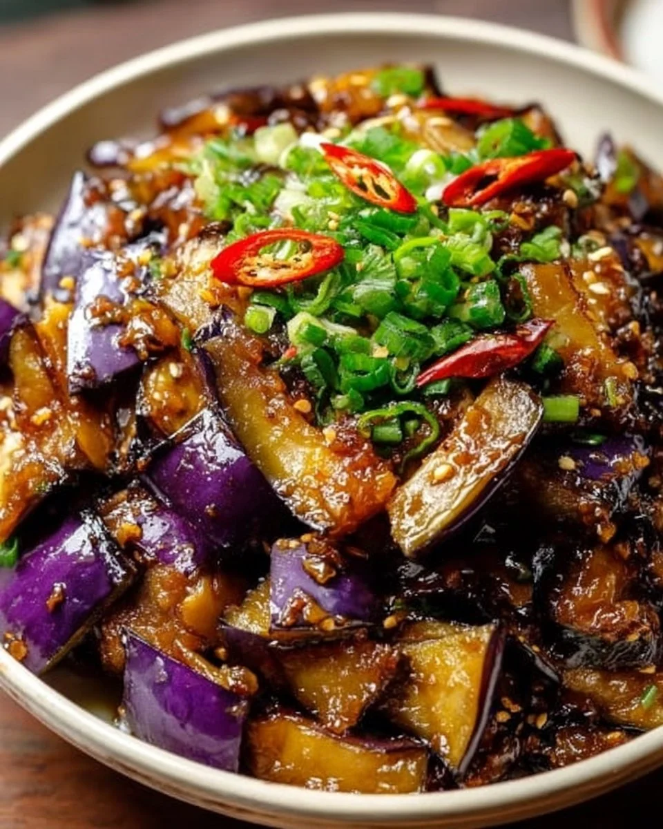 Chinese eggplant in garlic sauce served in a bowl, showcasing vibrant colors and textures.