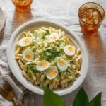 Bowl of creamy pasta salad with colorful vegetables and herbs