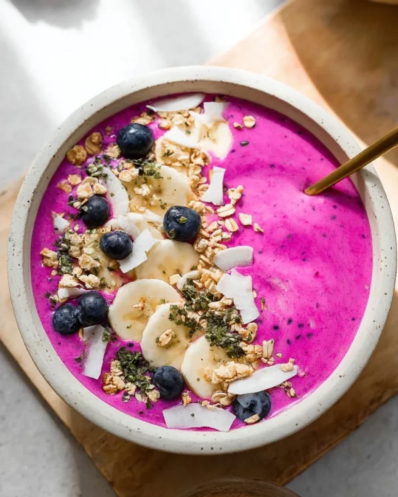 A vibrant dragon fruit smoothie bowl topped with fresh fruits and seeds
