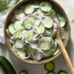Creamy German cucumber salad served in a bowl with fresh herbs