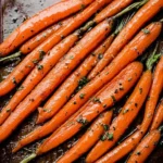 Honey balsamic roasted carrots garnished with herbs on a white plate.