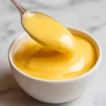 Creamy lemon curd served in a bowl, garnished with lemon zest and mint leaves.