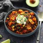 Bowl of hearty slow cooker Mexican quinoa topped with fresh avocado and cilantro.