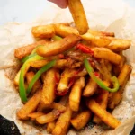 A bowl of delicious Salt and Chilli Chips garnished with fresh herbs.