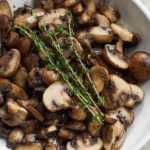 Plate of sautéed mushrooms garnished with fresh herbs and spices