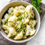 Simple steamed cauliflower with fresh herbs garnishing on a plate