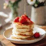 Fluffy Soufflé Pancakes topped with syrup and fresh fruit