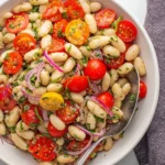 Creamy white bean salad in a bowl, garnished with vegetables and herbs