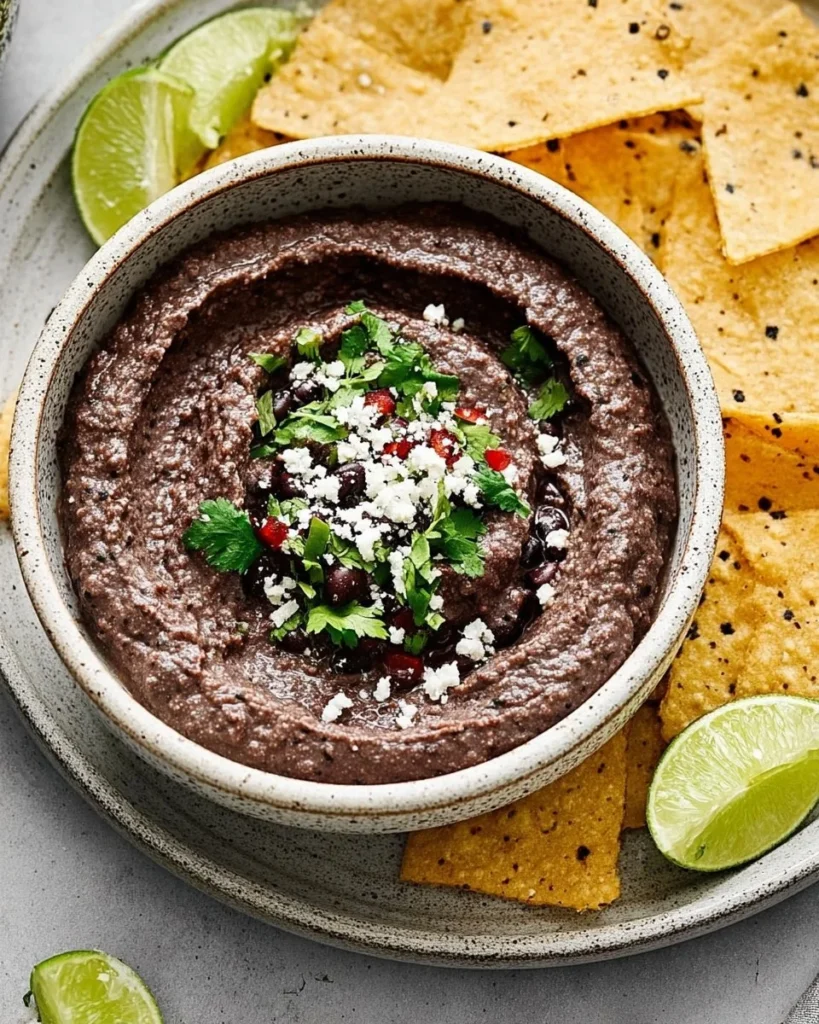 Delicious black bean dip served in a bowl with tortilla chips, perfect for parties.