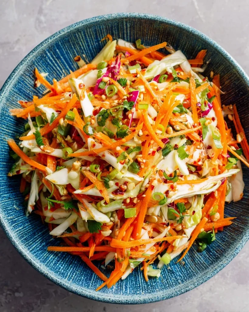 Colorful carrot cabbage salad with dressing and toppings, perfect for meal prep.