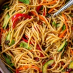 Bowl of cold sesame noodles topped with sesame seeds and vegetables