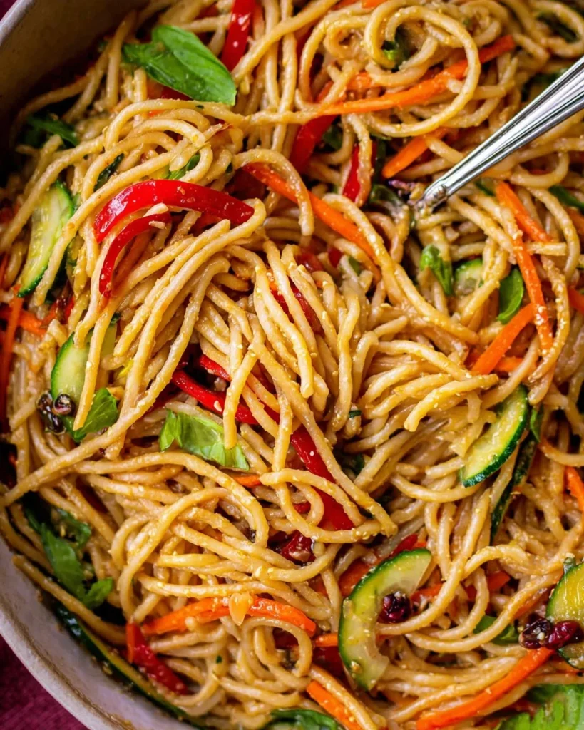 Bowl of cold sesame noodles topped with sesame seeds and vegetables