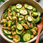 Fresh cucumber salad topped with herbs and dressing in a bowl