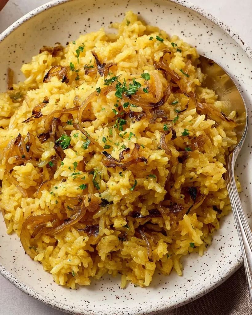 Golden Onion Butter Rice served in a white bowl with fresh herbs and spices