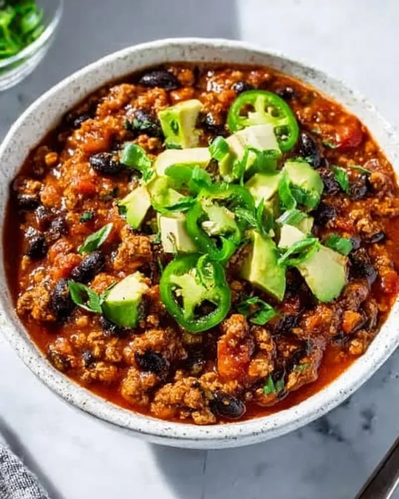 Delicious bowl of Ground Turkey Chili topped with fresh herbs and served with bread.