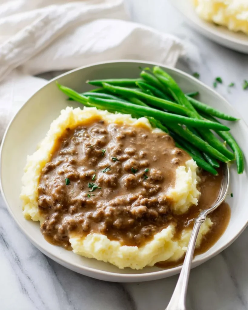 Bowl of savory hamburger gravy served over mashed potatoes.