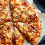 A delicious Hawaiian Pizza topped with ham and pineapple slices.