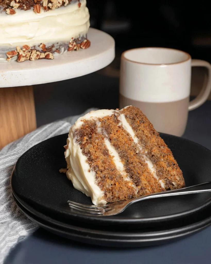 Delicious Hummingbird Cake topped with nuts and fruit slices on a plate.