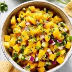 Fresh mango salsa in a bowl with colorful vegetables and herbs