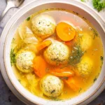 A warm bowl of Matzo Ball Soup with fluffy matzo balls and fresh herbs