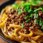 Delicious Mongolian ground beef noodles with veggies served in a bowl.