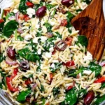 Colorful orzo salad with feta cheese and fresh spinach served in a bowl