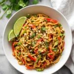 Delicious peanut butter noodles garnished with green onions and peanuts.