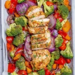 Sheet pan baked chicken breast with colorful veggies on a serving plate
