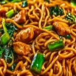 Sticky Garlic Chicken Noodles in a bowl garnished with herbs