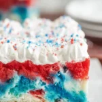 Colorful 4th of July Jello Cake topped with whipped cream and berries