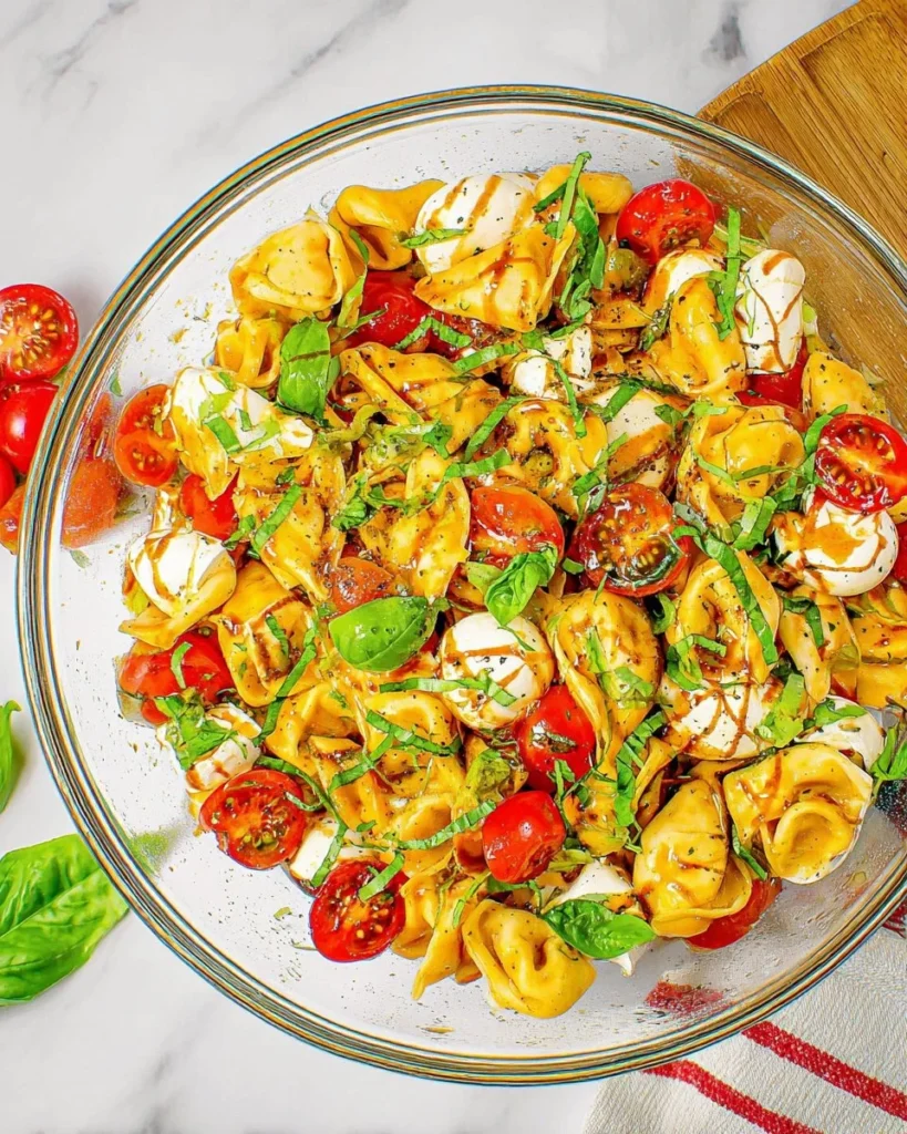 Colorful Caprese Tortellini Pasta Salad with mozzarella, tomatoes, and basil.