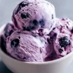 Creamy blueberry cottage cheese ice cream in a bowl with fresh blueberries