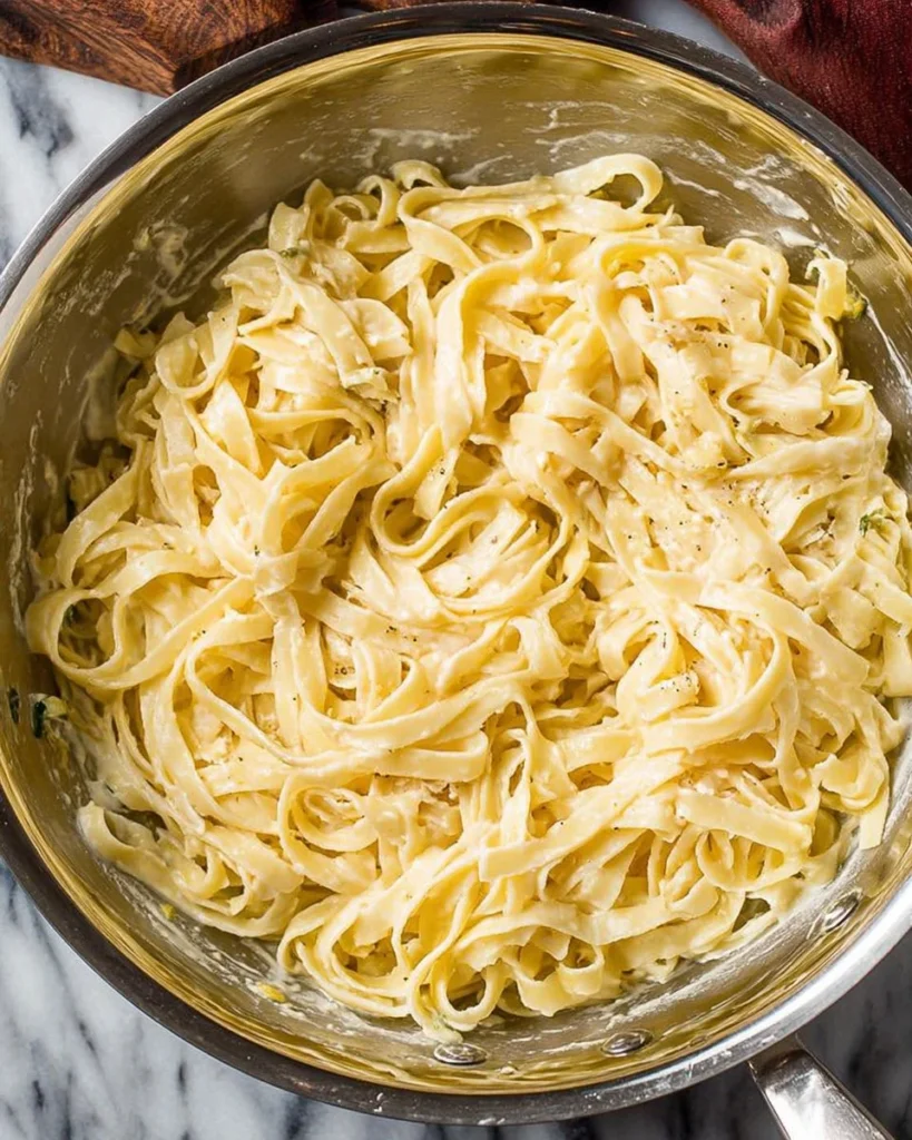 Plate of lighter fettuccine alfredo topped with parsley and parmesan cheese.