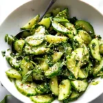 Smashed cucumber salad with fresh herbs and dressing in a bowl