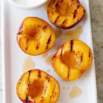 Grilled peaches topped with honey and yogurt served on a plate