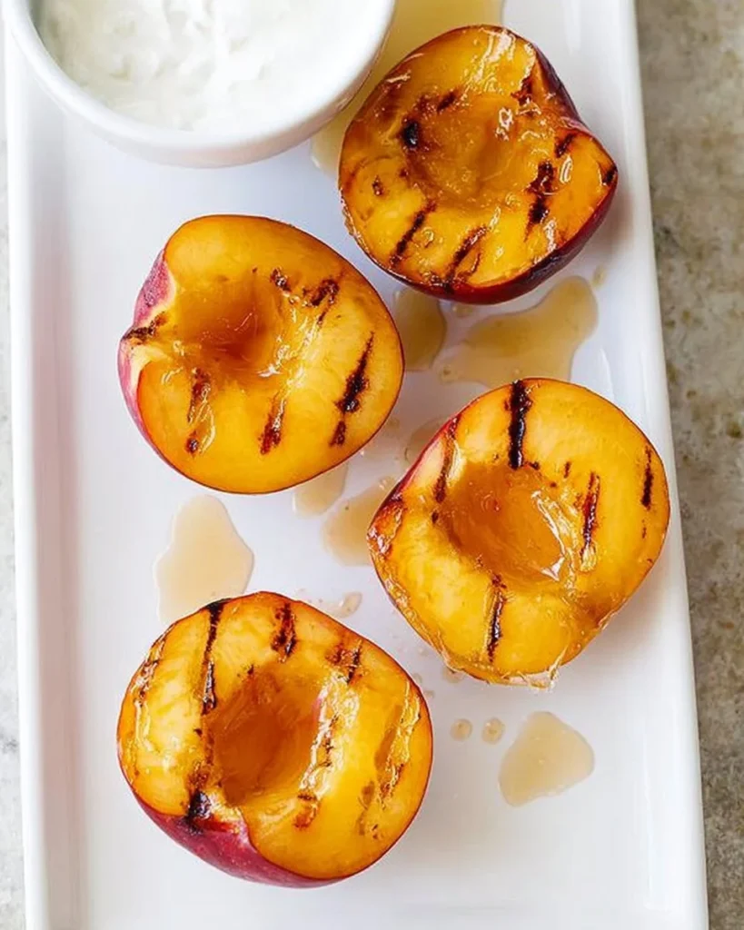 Grilled peaches topped with honey and yogurt served on a plate