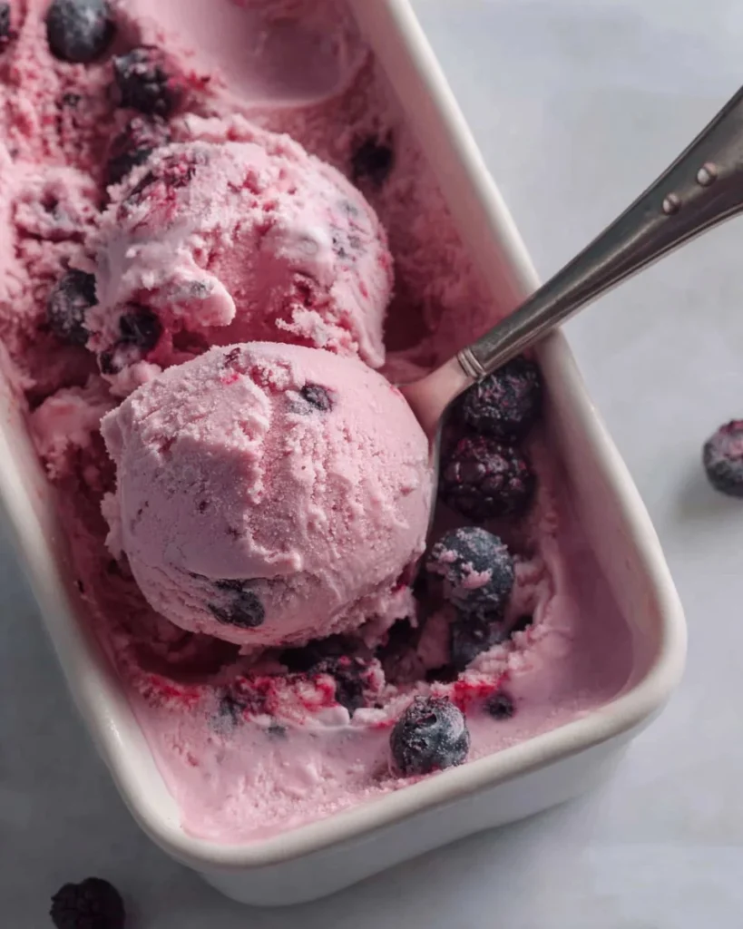 A bowl of homemade berry frozen yogurt topped with fresh berries and mint.
