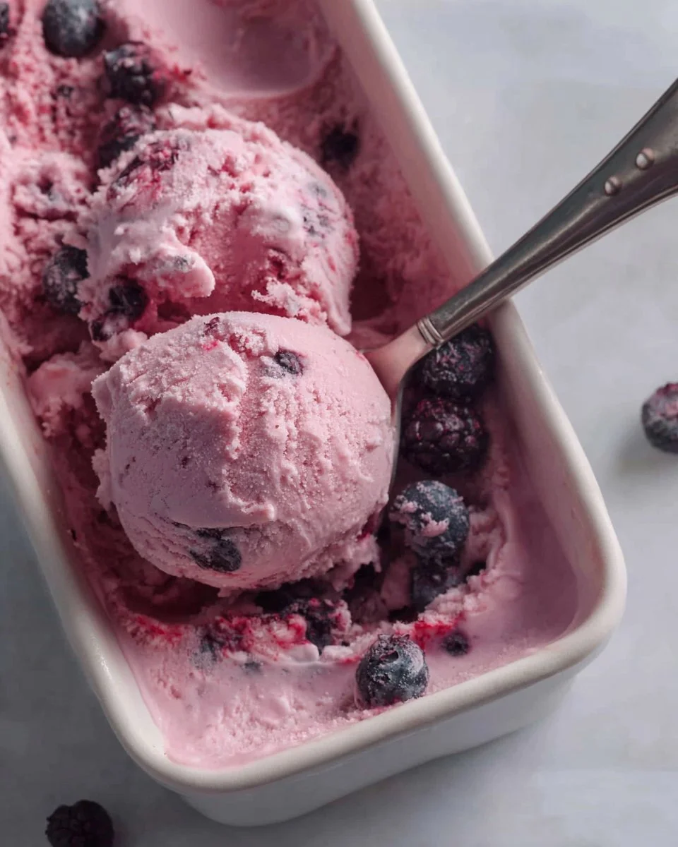 A bowl of homemade berry frozen yogurt topped with fresh berries and mint.
