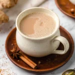 A steaming cup of spiced chai with aromatic spices and tea leaves.