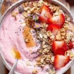 Delicious strawberry smoothie bowl topped with fresh strawberries and granola