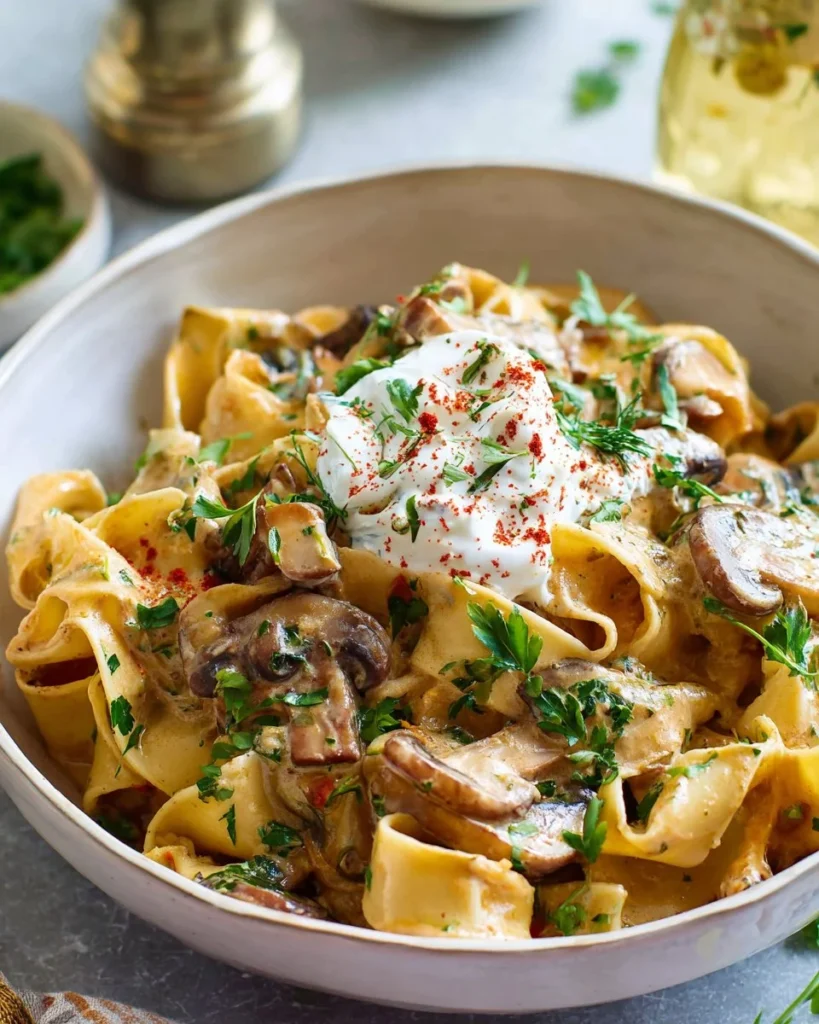 A bowl of creamy Vegetarian Stroganoff garnished with herbs and mushrooms.