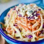 Delicious blue cheese coleslaw served in a bowl, garnished with fresh herbs.